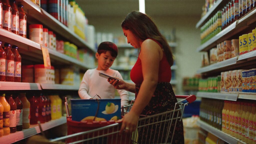 Mãe e filho comparam preços no corredor de um supermercado de bairro